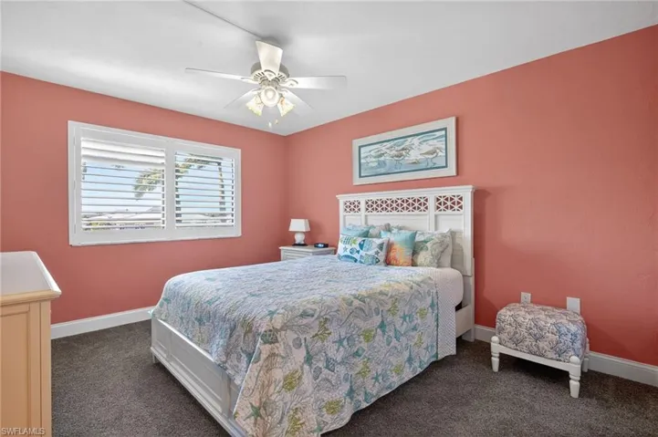 Bedroom with ceiling fan and dark colored carpet