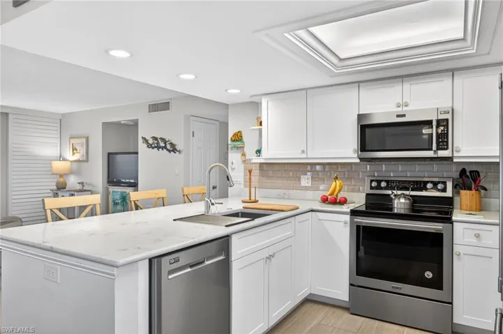 Kitchen featuring stainless steel appliances, a peninsula, white cabinetry, and recessed lighting