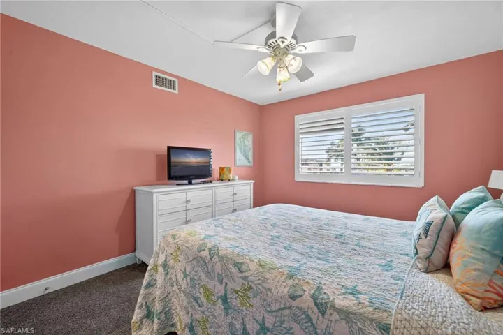 Bedroom with dark carpet and a ceiling fan