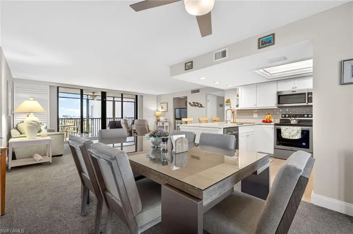 Dining area featuring ceiling fan, light colored carpet, and floor to ceiling windows