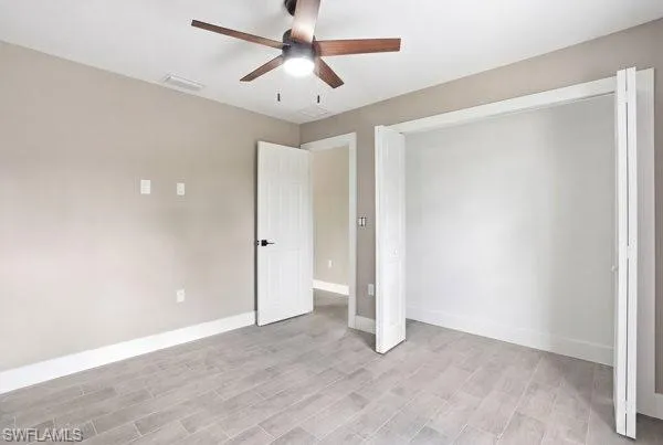 Wood-look tile flooring, neutral wall tones, modern ceiling fan with integrated lighting, and white bi-fold closet doors