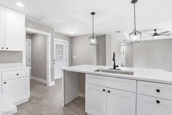 Kitchen featuring white shaker cabinetry, light-toned countertops, a matte black faucet, and pendant lighting