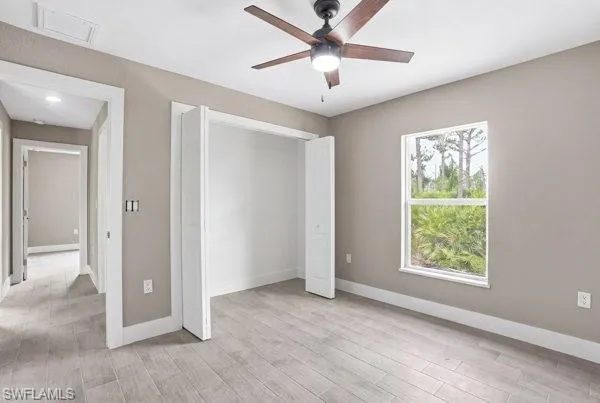 Room featuring light wood-finish flooring, a ceiling fan with integrated lighting, a spacious window, and a bi-fold closet