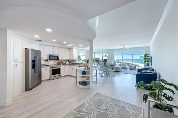 Kitchen featuring stainless steel appliances, open floor plan, white cabinetry, light wood finished floors, and recessed lighting
