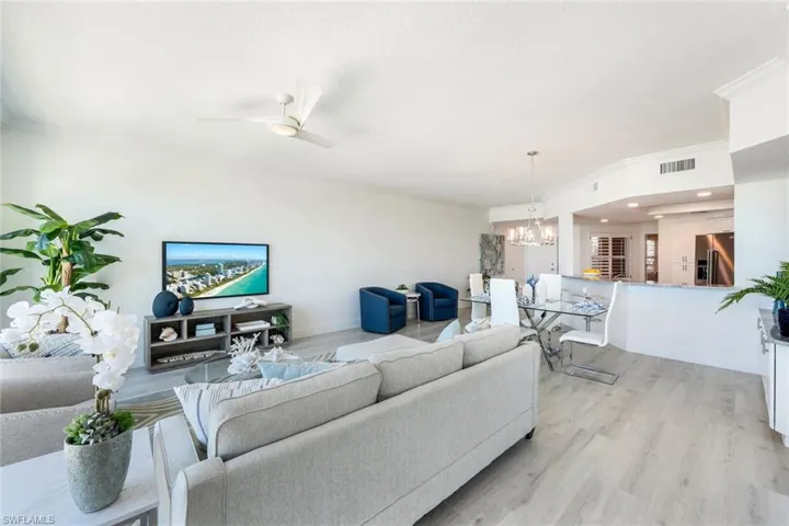 Living room featuring a chandelier, light wood-style floors, baseboards, and ceiling fan