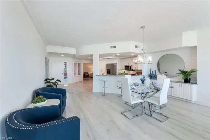 Dining area featuring ornamental molding, a chandelier, light wood-type flooring, a textured ceiling, and baseboards