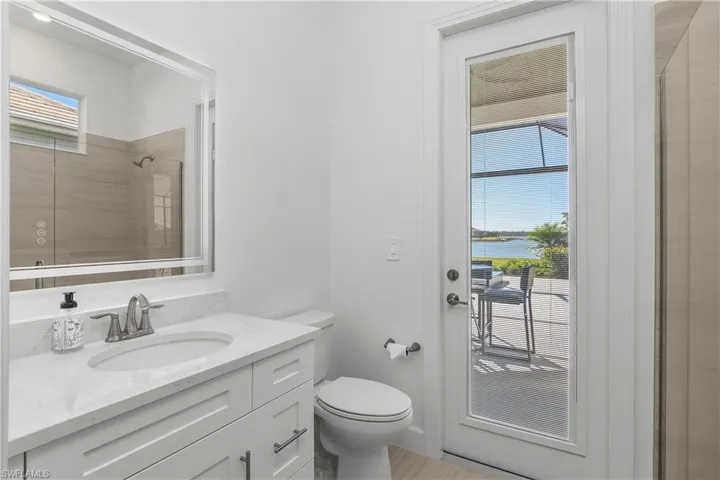 Ensuite bathroom serves as a pool bath leading to the lanai and pool and includes a walk-in shower and custom backlit mirror.