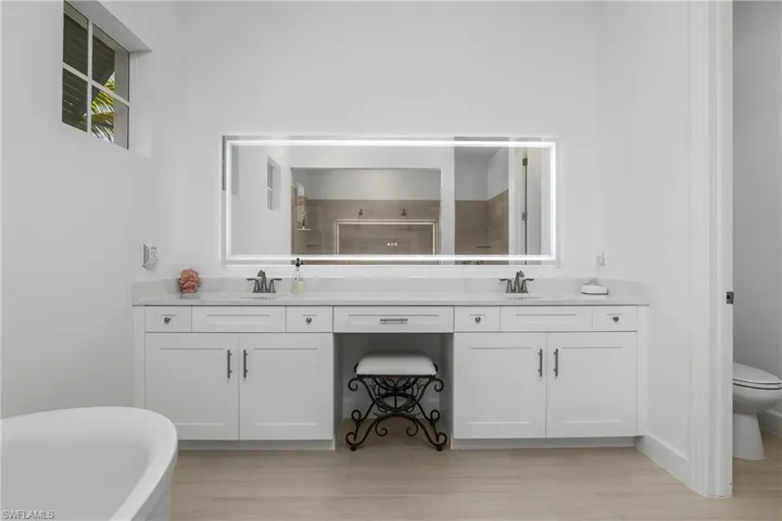 Primary bath is a true retreat with soaking tub, dual sink vanity, custom backlit mirrors, and oversized walk-in shower.