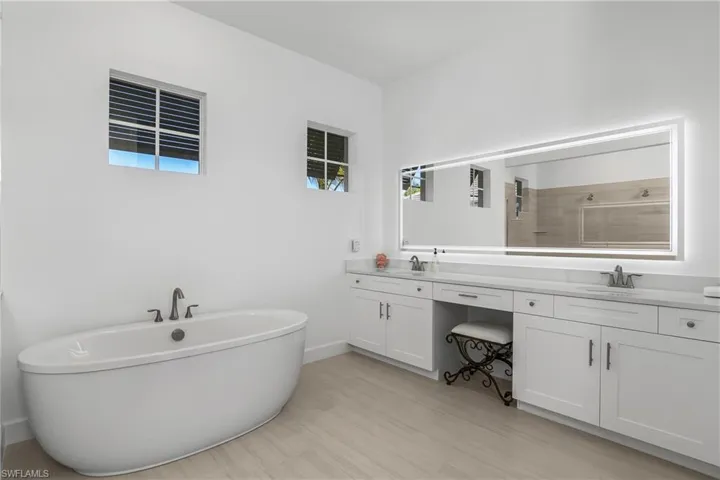 Primary bath is a true retreat with soaking tub, dual sink vanity, custom backlit mirrors, and oversized walk-in shower.