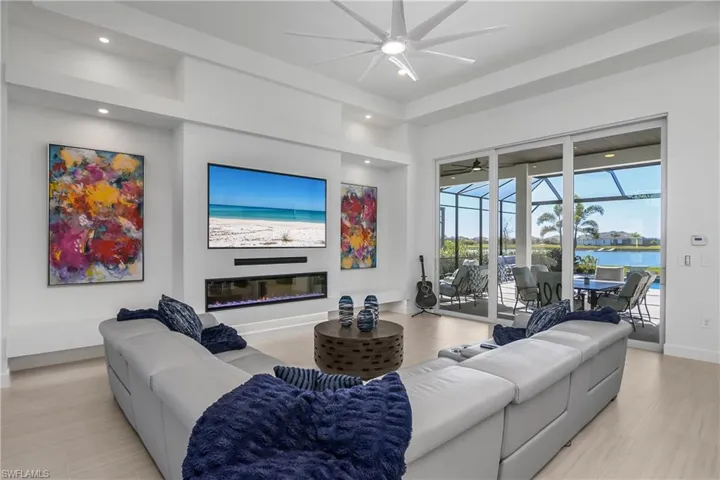 Great room features a lighted custom-built feature wall with 74" electric fireplace & dual floating custom cabinets, and 84" Wifi Troposair lighted ceiling fan.