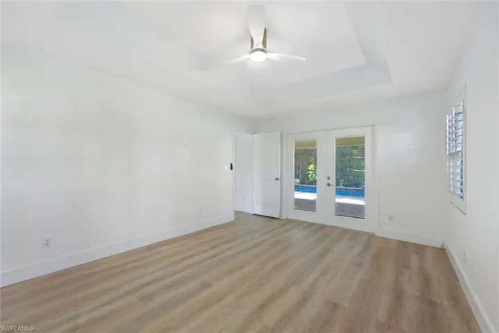 Primary Bedroom featuring a tray ceiling, a chandelier, and light wood-style floors