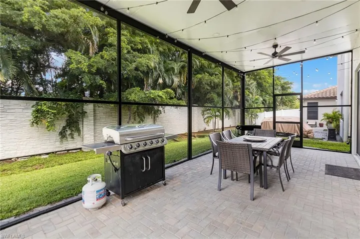 Screened patio featuring a ceiling fan, string lighting, and paver flooring