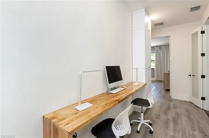 Built-in wood-finish desk with modern white cabinetry