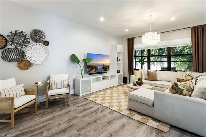 Recessed lighting, wood-finish flooring, and a large window with white blinds and dark curtain rods