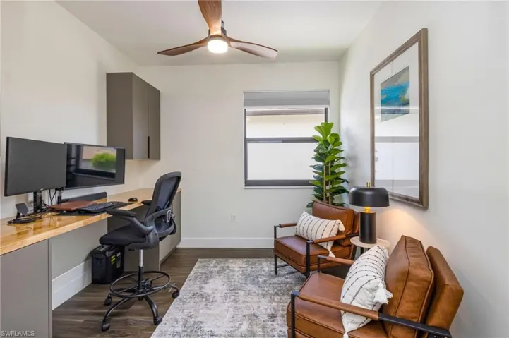 Built-in desk with wood-finish countertop, coordinating overhead and lower cabinetry, wood-finish flooring, and a ceiling fan with integrated lighting