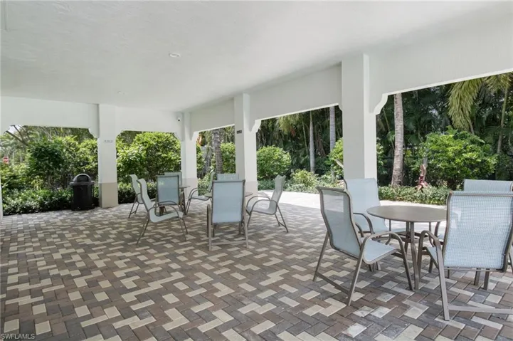 Covered patio featuring a multi-tone paver floor and lush perimeter landscaping