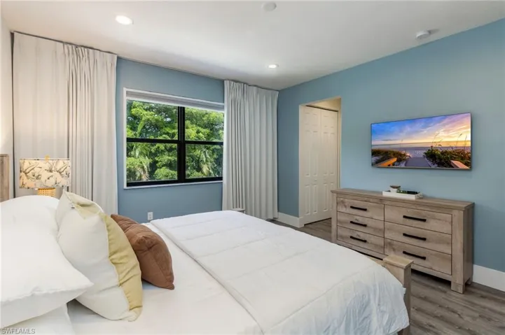 Recessed lighting, wood-finish flooring, and a large window with white drapery