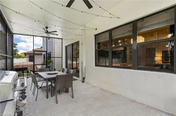 Screened outdoor patio featuring a ceiling fan, string lighting, and tiled flooring