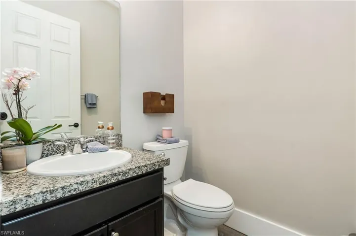Granite countertop, under-mount sink, dark wood-finish vanity, chrome fixtures, and white toilet