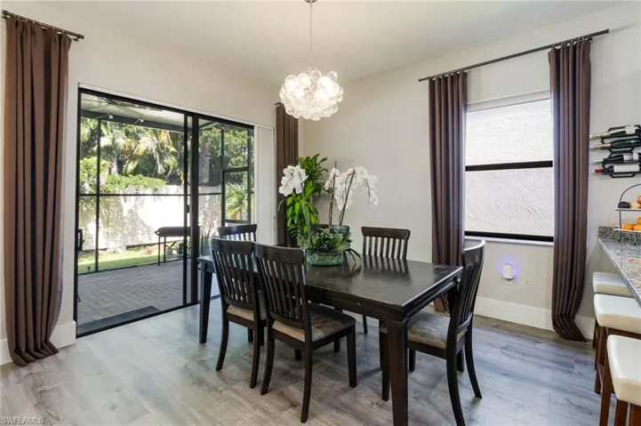 Wood-finish flooring throughout, sliding glass doors to outdoor space, overhead chandelier, and a built-in wine rack