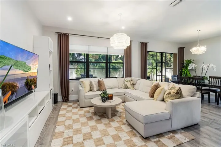 Open-concept living space with wood-finish flooring, recessed lighting, and large windows