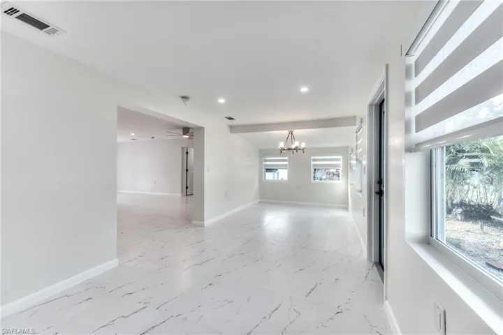 Spare room with ceiling fan with notable chandelier