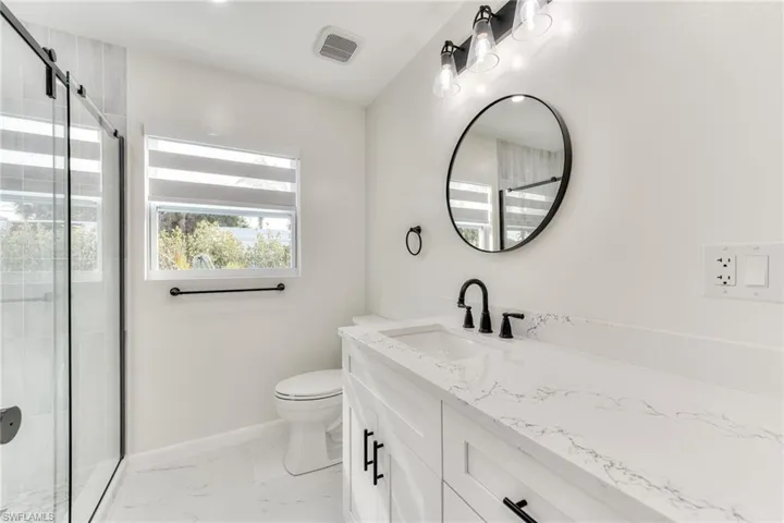 Bathroom featuring toilet, vanity, and walk in shower