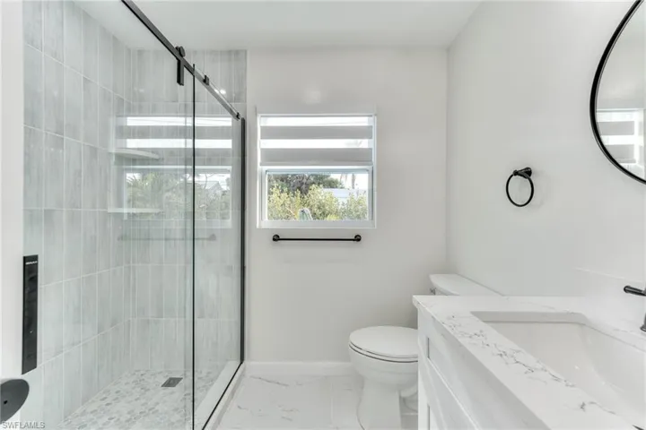 Bathroom with toilet, walk in shower, and vanity