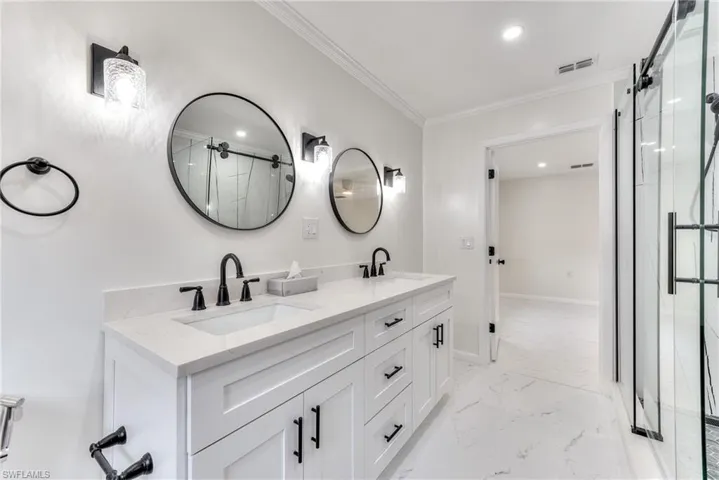 Bathroom with vanity, crown molding, and an enclosed shower