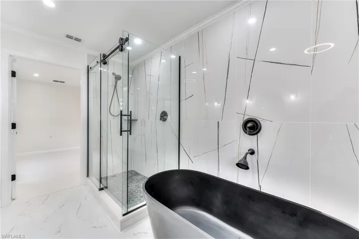 Bathroom featuring ornamental molding and separate shower and tub