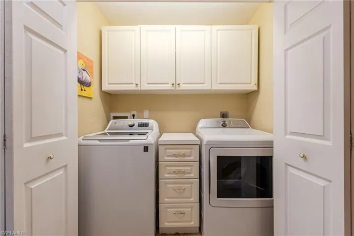 Washroom with washer and clothes dryer and cabinet space