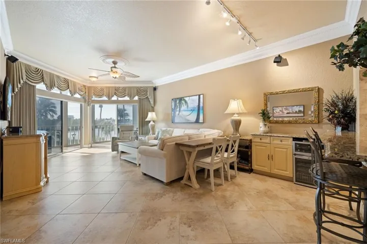 Living room featuring crown molding, a textured ceiling, a ceiling fan, a water view, and track lighting