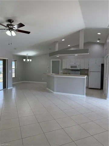 Unfurnished living room featuring a ceiling fan, suspended lighting, light tile patterned flooring, and lofted ceiling
