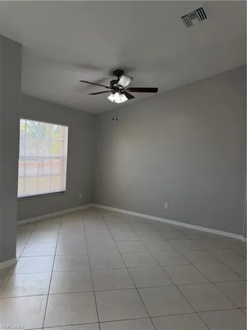 Empty room featuring a ceiling fan and light tile patterned floors