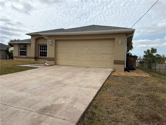 View of front of house with stucco siding, concrete driveway, a garage, and a shingled roof