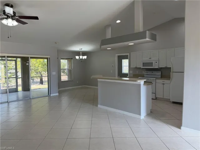 Kitchen featuring white appliances, open floor plan, white cabinets, light countertops, and lofted ceiling