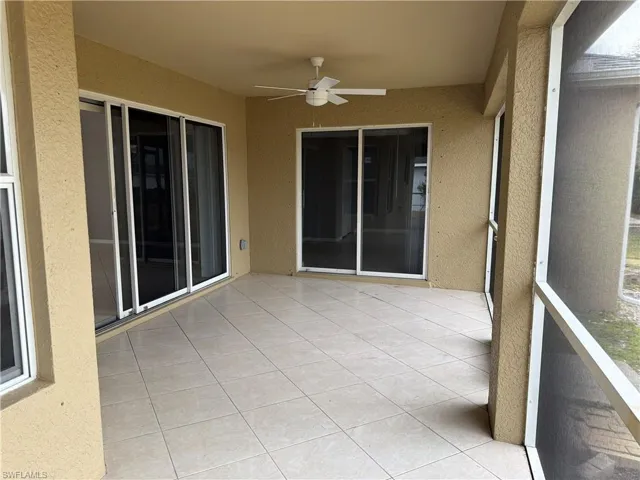 Unfurnished sunroom with a ceiling fan and a patio area
