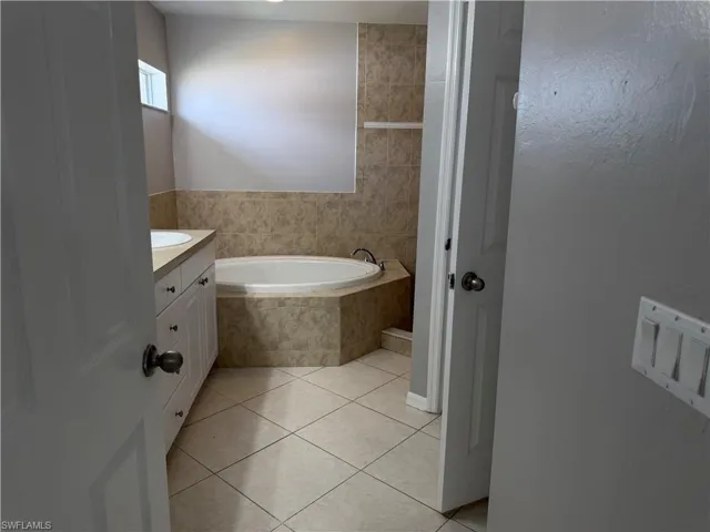 Bathroom featuring vanity, a bath, and light tile patterned flooring