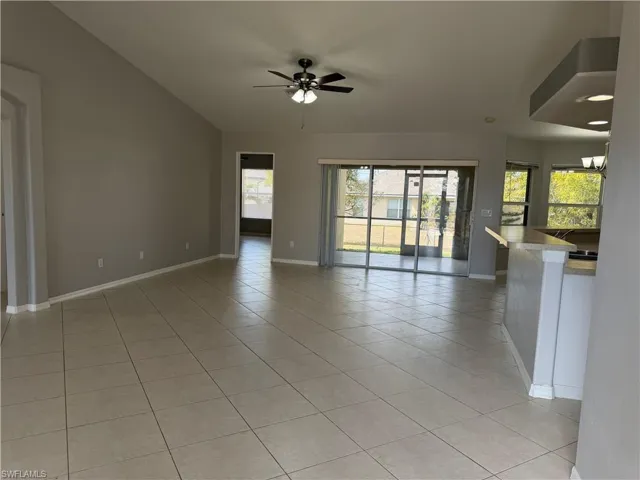 Unfurnished room featuring light tile patterned flooring, ceiling fan, vaulted ceiling, and hanging lights