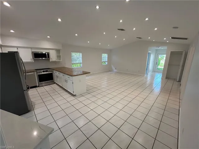 Kitchen with white cabinets, light tile patterned flooring, a peninsula, stainless steel appliances, and recessed lighting