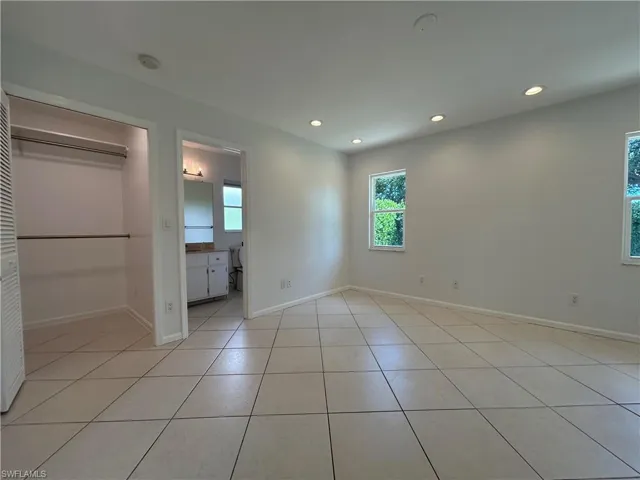 Unfurnished bedroom featuring recessed lighting, light tile patterned floors, a closet, and ensuite bath