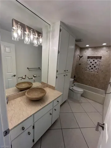 Bathroom featuring shower / bathtub combination, vanity, and light tile patterned floors