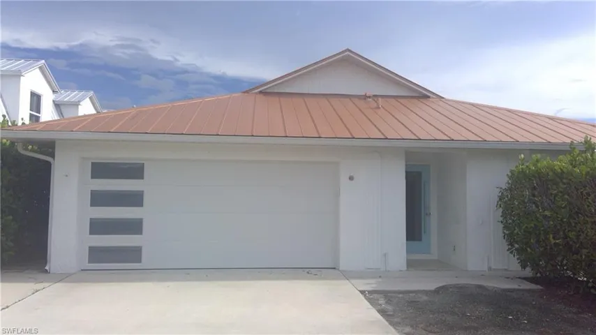View of front of home featuring a standing seam roof, a metal roof, an attached garage, and concrete driveway