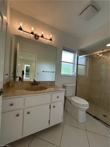 Bathroom with vanity, healthy amount of natural light, a stall shower, and light tile patterned floors
