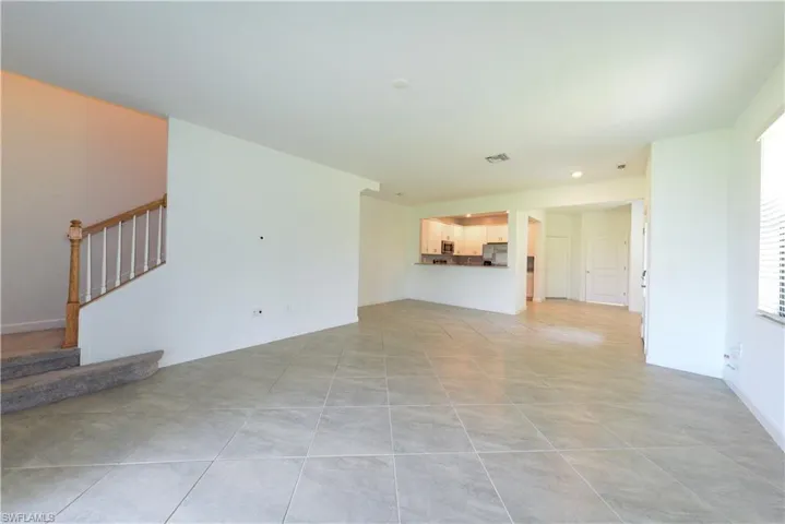Unfurnished living room with light tile patterned flooring and stairs