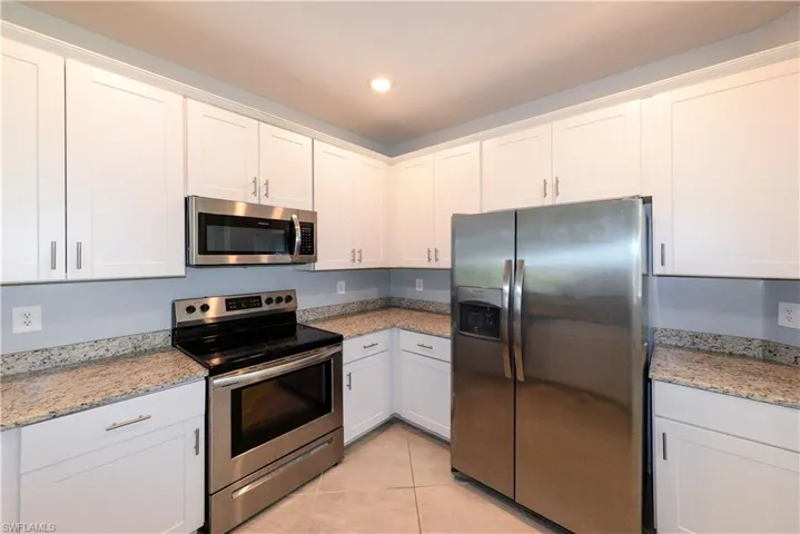 Kitchen with appliances with stainless steel finishes, white cabinetry, light stone counters, and recessed lighting