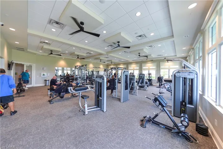 Exercise room featuring a tray ceiling, recessed lighting, a drop ceiling, carpet, and ceiling fan