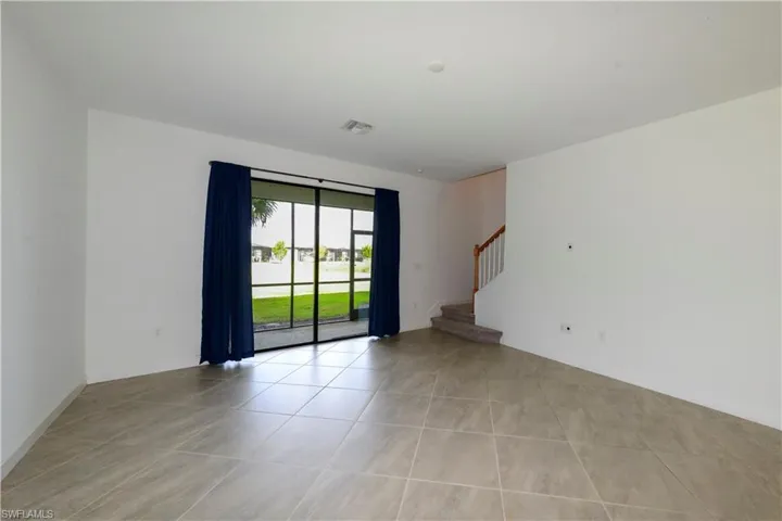 Spare room with light tile patterned flooring and stairway