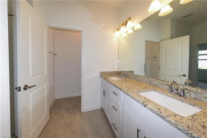 Full bathroom featuring double vanity and light tile patterned floors