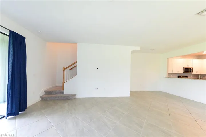 Unfurnished living room featuring light tile patterned floors and stairs
